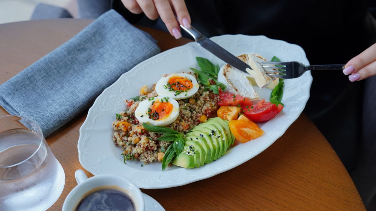 A delicious and healthy breakfast featuring avocado, eggs, and coffee served on a wooden table.